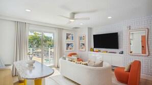 Ein modernes Wohnzimmer mit einem weißen Sofa, einem orangefarbenen Sessel und einem flachbildfernseher an der Wand.