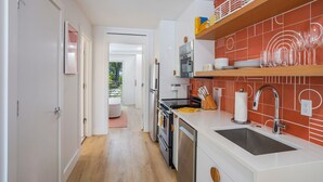 Eine moderne Küche mit weißen Schränken, einer Edelstahl-Spüle und einer roten Fliesenrückwand.