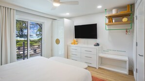 Un dormitorio moderno con cama, televisor, escritorio y balcón con vistas.