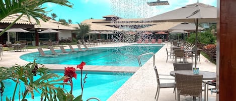 A pool area with a water feature, outdoor seating, and a covered patio.