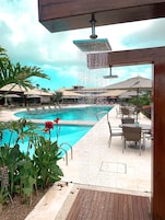 Un área de piscina con fuente de agua, mobiliario exterior y un porche cubierto.