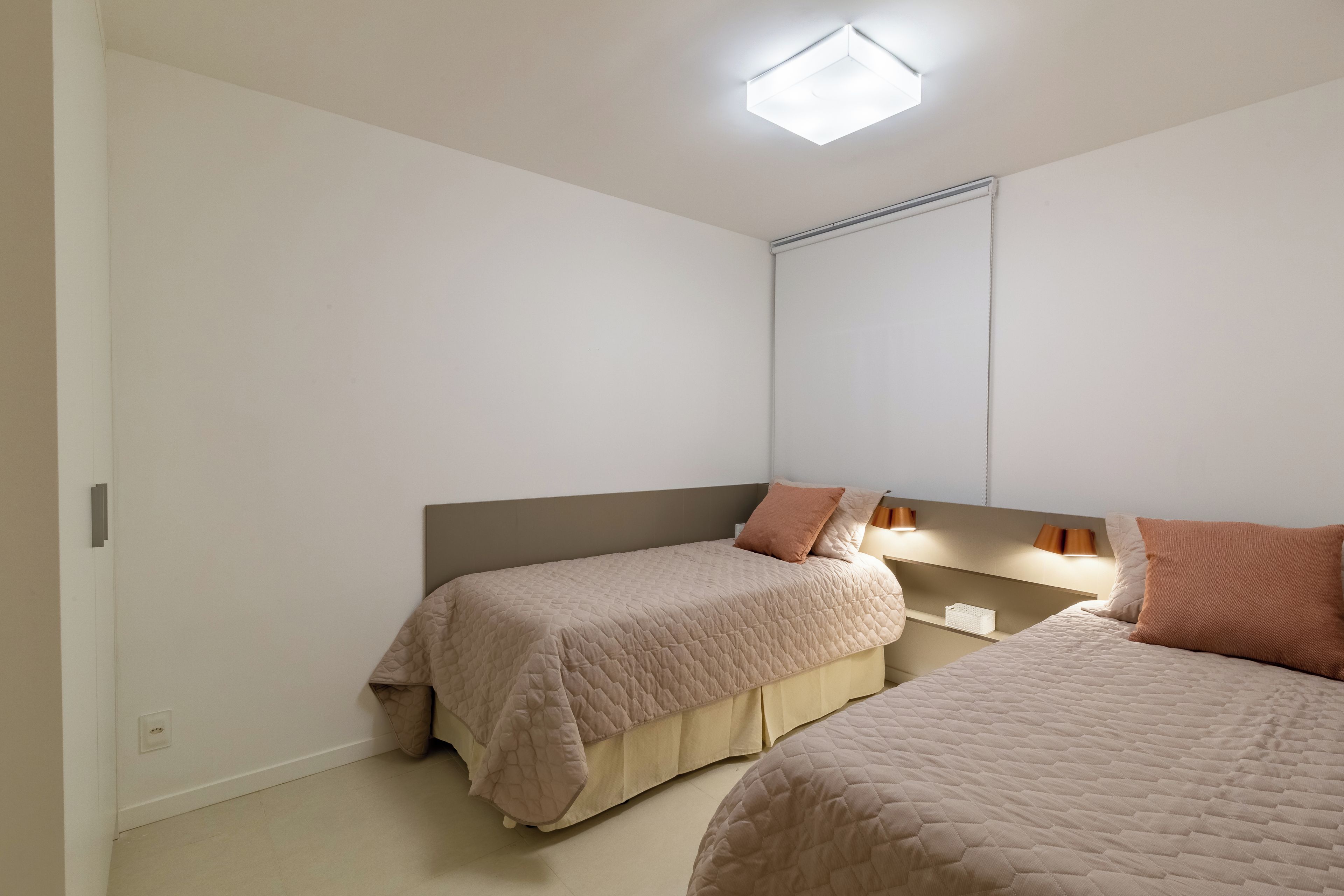 Un dormitorio con dos camas, una lámpara de techo y un espejo.