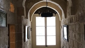 Ein schmaler Steinprospekt mit hoher Decke, einem großen Rundbogen und einer hängenden Leuchte.