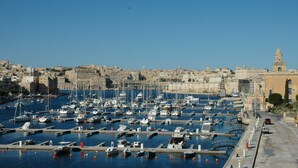 Ein Yachthafen mit zahlreichen Schiffen, die in einem Hafen vor Anker liegen, umgeben von historischen Gebäuden und einem markanten Turm.