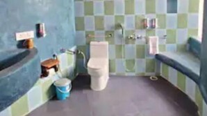 Une salle de bain avec un mur recouvert de carreaux à motifs, des toilettes, un lavabo et un espace douche.