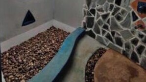 Une pièce dotée d’une lucarne, d’un mur décoré de mosaïques et d’un lit avec une t ête de lit bleue.