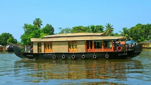Ein traditionelles Hausboot mit einem Reetdach, mehreren Fenstern und einem überdachten Deck.