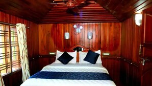 Ein Zimmer mit Holzwandverkleidung, einem Bett, zwei Wandleuchten und einem Deckenventilator.