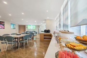 Un comedor moderno con una barra larga, asientos y un bufé de frutas.