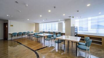 Une salle de conférence dotée d’une longue table et de chaises, de grandes fenêtres et d’un plancher en bois.