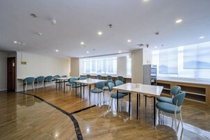 Un salón de conferencias con una larga mesa y sillas, ventanas amplias y piso de madera.