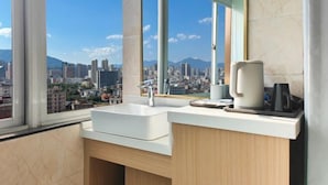 Casa de banho moderna com uma janela grande, uma pia e uma máquina de café.