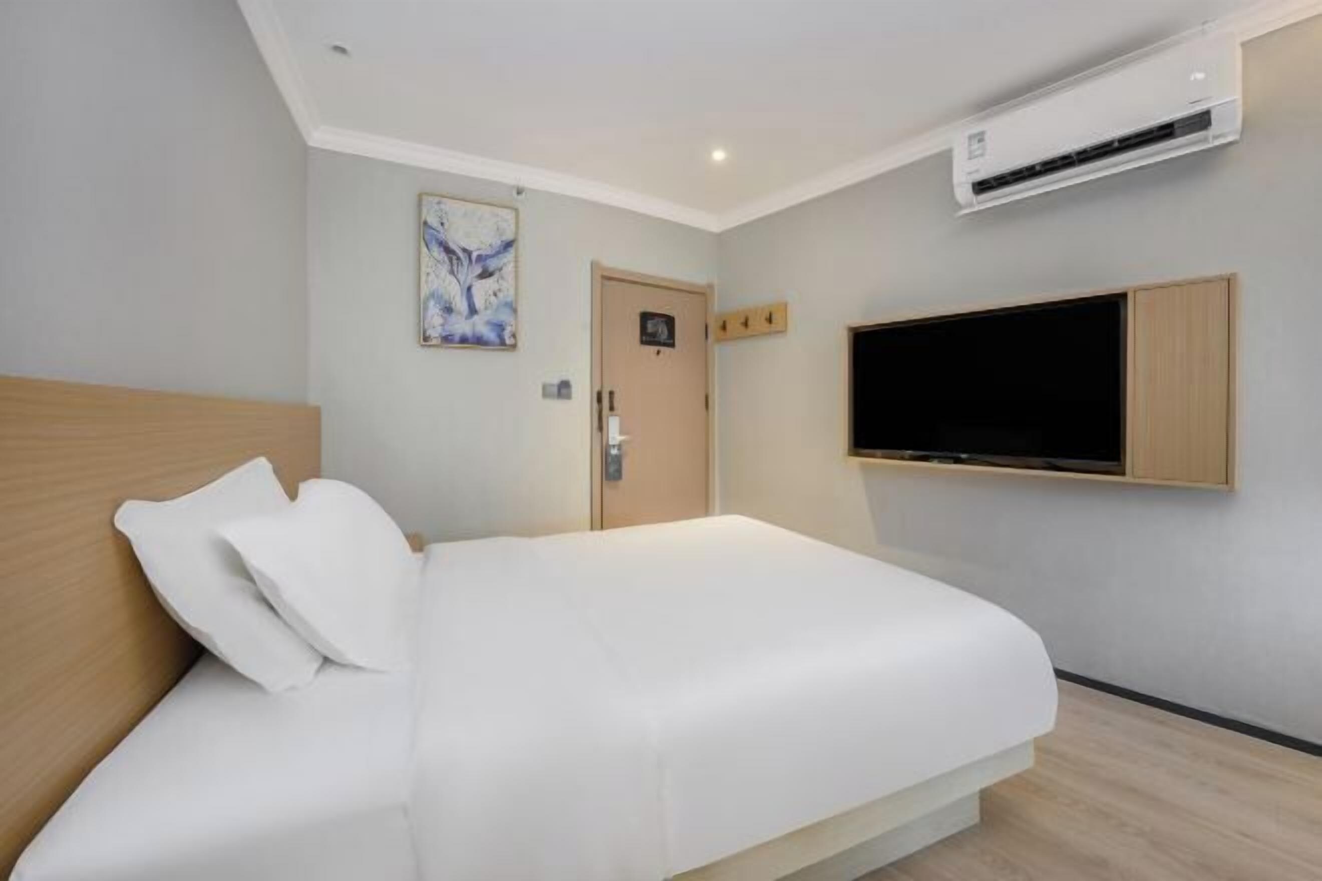 Une chambre d’hôtel moderne équipée d’un lit, d’un téléviseur fixé au mur et d’un appareil de climatisation.