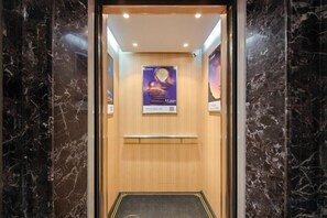 A marble-floored elevator with a wooden interior and a poster on the wall. - ManZhou International Hotel (Anxi Tea City) (Anxi)
