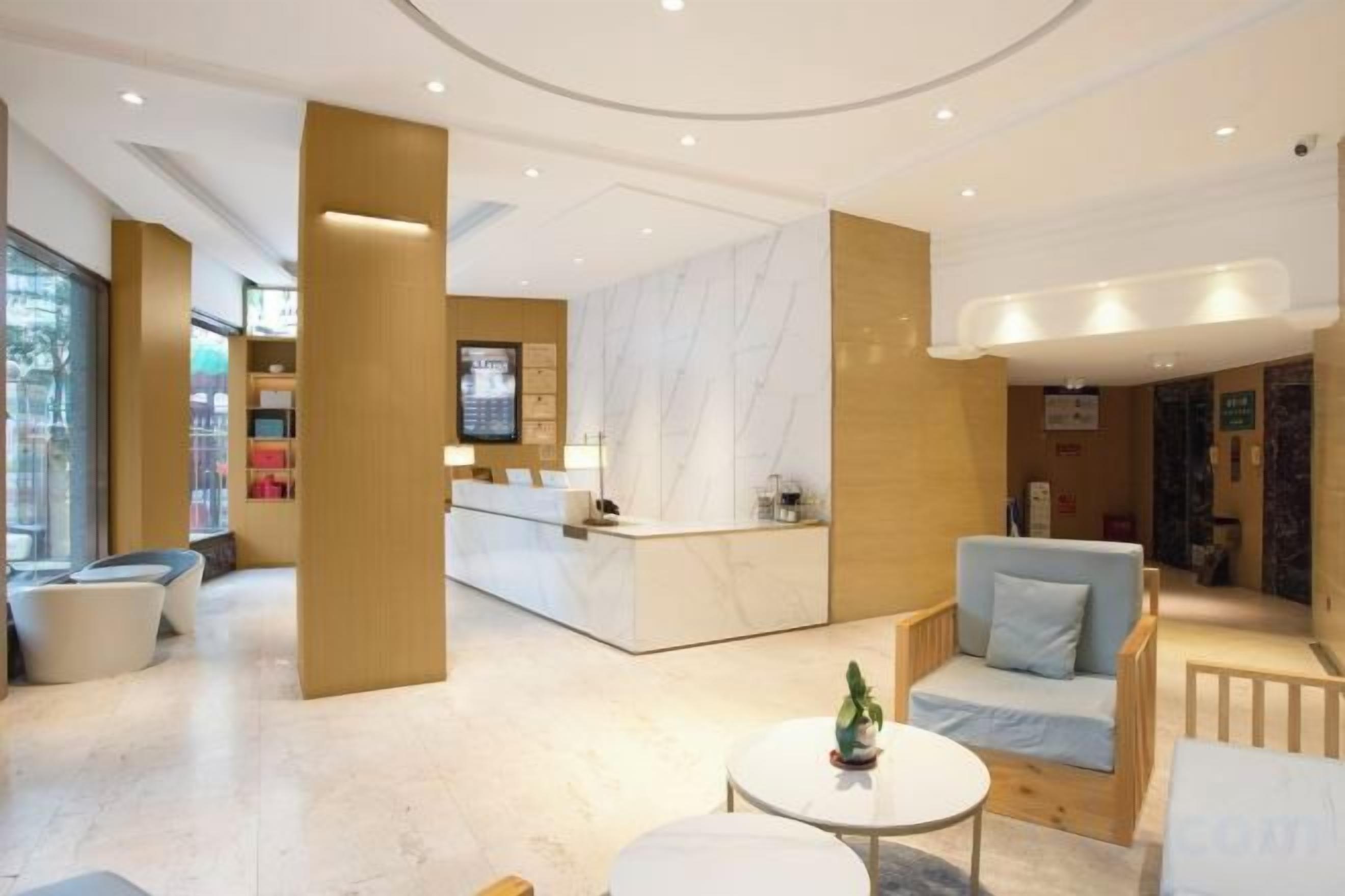 A hotel lobby with a reception desk, seating area, and a large window.