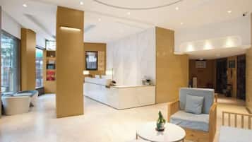 A hotel lobby with a reception desk, seating area, and a large window.