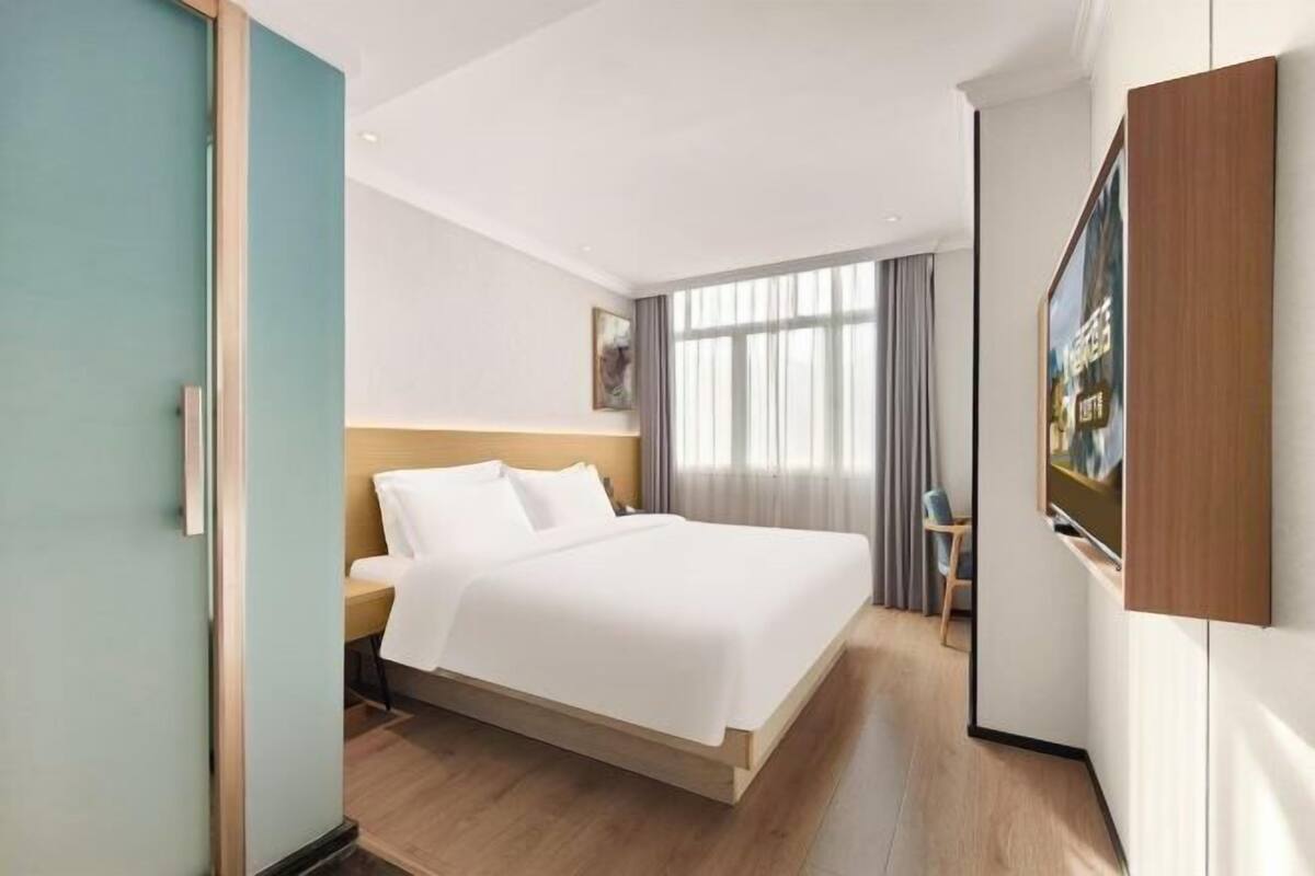 Une chambre d’hôtel moderne avec un grand lit, un bureau et une télévision.