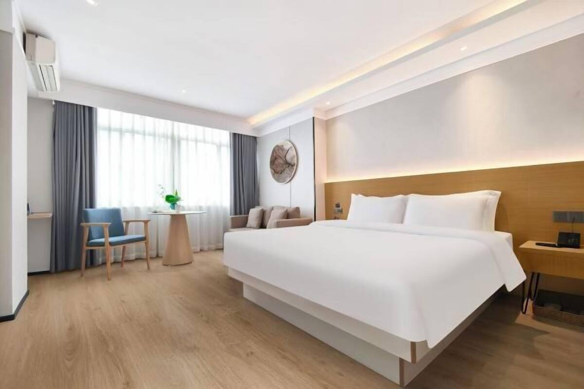 Une chambre d’hôtel moderne avec un grand lit, un bureau, une chaise et une petite table.