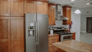 A kitchen with wooden cabinets, stainless steel appliances, and a granite countertop.
