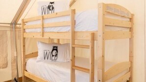 A bunk bed with two pillows, one with a bear design, in a tent-like room with a wooden floor. - Deluxe Safari Tent Glamping at Unicoi in Helen GA - 15 (Helen)