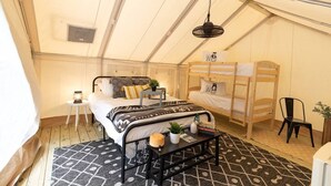 A tented room with a bed, a bunk bed, a small table with a plant, and a hanging light fixture. - Safari Tent Glamping at Unicoi in Helen GA - 12 (Helen)