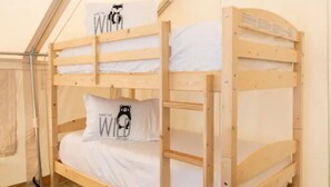 Een stapelbed met twee kussens, waarvan één met een ontwerp van een beer, in een kamer met een kamerkleed met patroon en houten vloer.