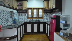 Uma cozinha com painel de azulejos, uma janela, uma pia, um fogão e uma geladeira.