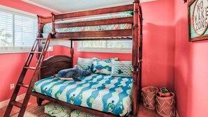 Un letto a castello con una scala, una coperta colorata e un cartello con la scritta 'NO WAKE ZONE'.