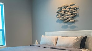 A bedroom with a bed, pillows, a headboard, a wall art piece, and a window. - Family-Friendly! (Gulfport)