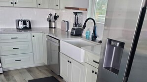 A modern kitchen with white cabinets, a stainless steel refrigerator, a toaster, and a blender on the countertop. - Family-Friendly! (Gulfport)
