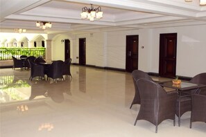 A spacious lobby with a polished floor, a seating area with wicker chairs and tables, and a balcony with a railing. - Zhonghui Hotel (Lingchuan)