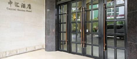 A hotel entrance with a sign reading "Central Garden Hotel" and a set of double doors with a glass panel.