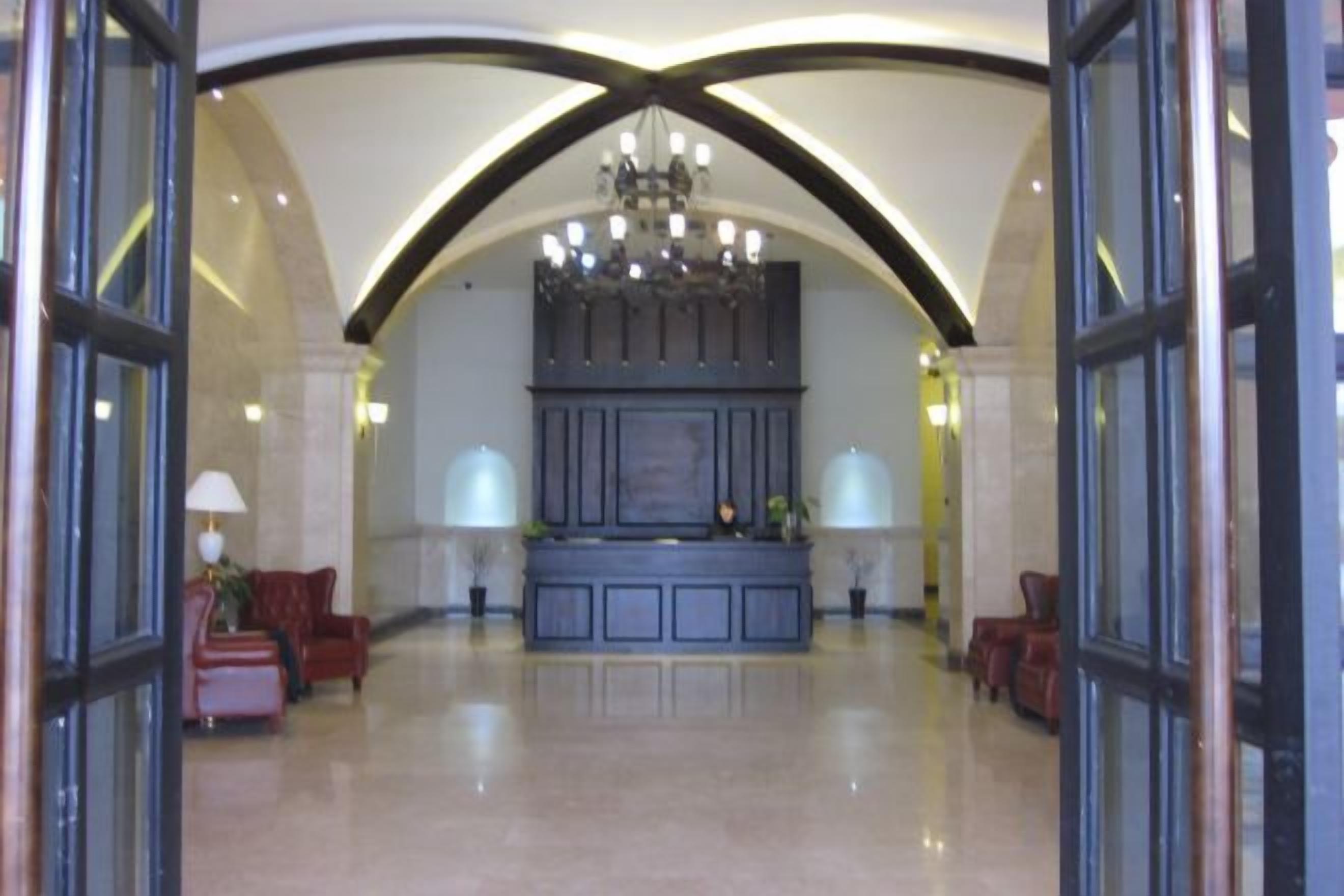 A lobby with a grand chandelier, a reception desk, and seating areas.