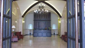 A lobby with a grand chandelier, a reception desk, and seating areas.