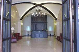 A lobby with a grand chandelier, a reception desk, and seating areas.