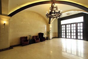 A spacious lobby with a high ceiling, a chandelier, and a seating area with leather chairs. - Zhonghui Hotel (Lingchuan)