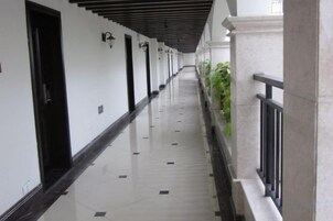 Un pasillo con puertas, una barandilla y una planta.