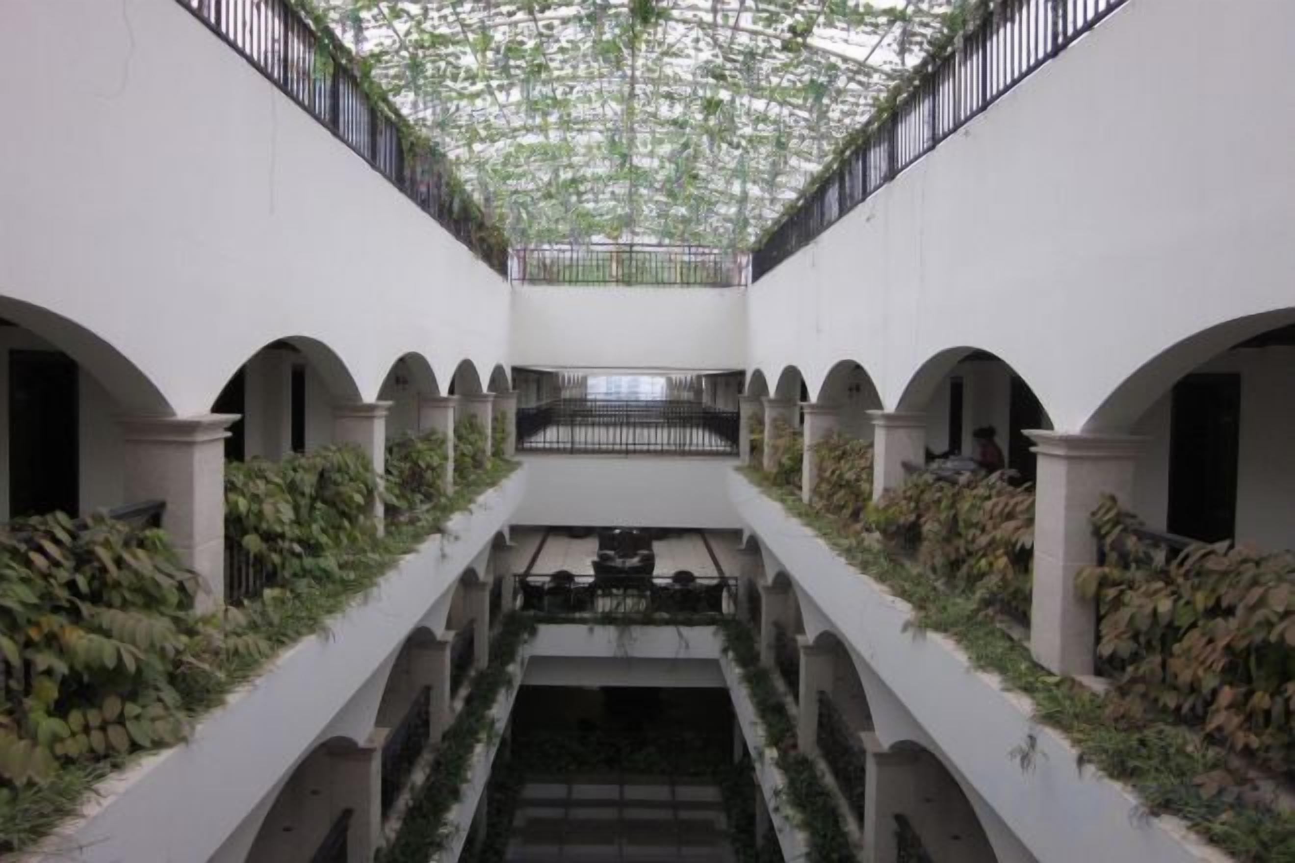 A courtyard with arches, a central staircase, and greenery.