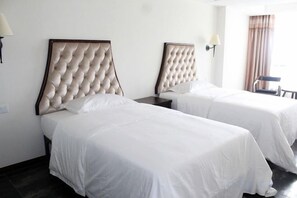 A hotel room with two beds, each with a tufted headboard, white bedding, and a nightstand with a lamp. - Zhonghui Hotel (Lingchuan)