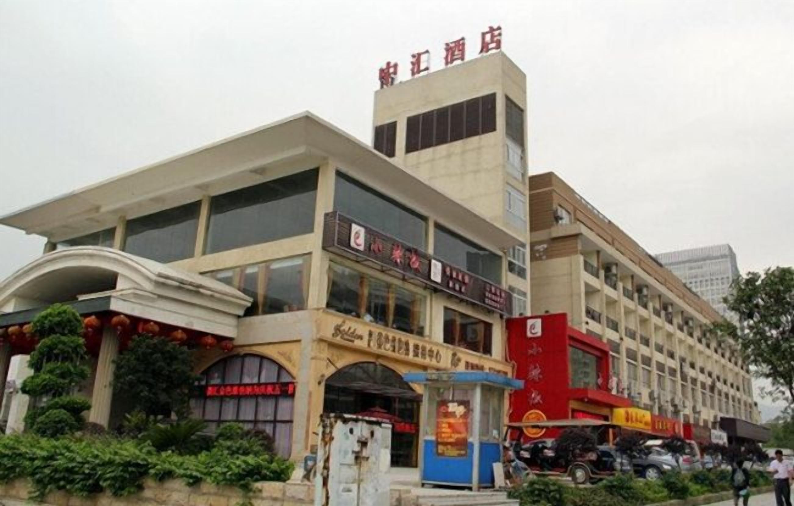Un edificio de varios pisos con letreros de un hotel y varios comercios.
