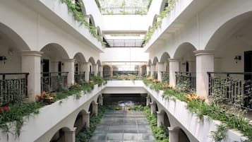 Un atrio de varios niveles con una escalera central, columnas y vegetación.