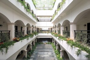 A multi-level atrium with a central staircase, columns, and greenery. - Zhonghui Hotel (Lingchuan)