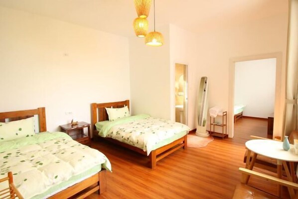 A bedroom with two wooden beds, a small table, and a mirror. - Huaqiao Hongying Inn (Guilin Dongxi Alley Shop) (Guilin)