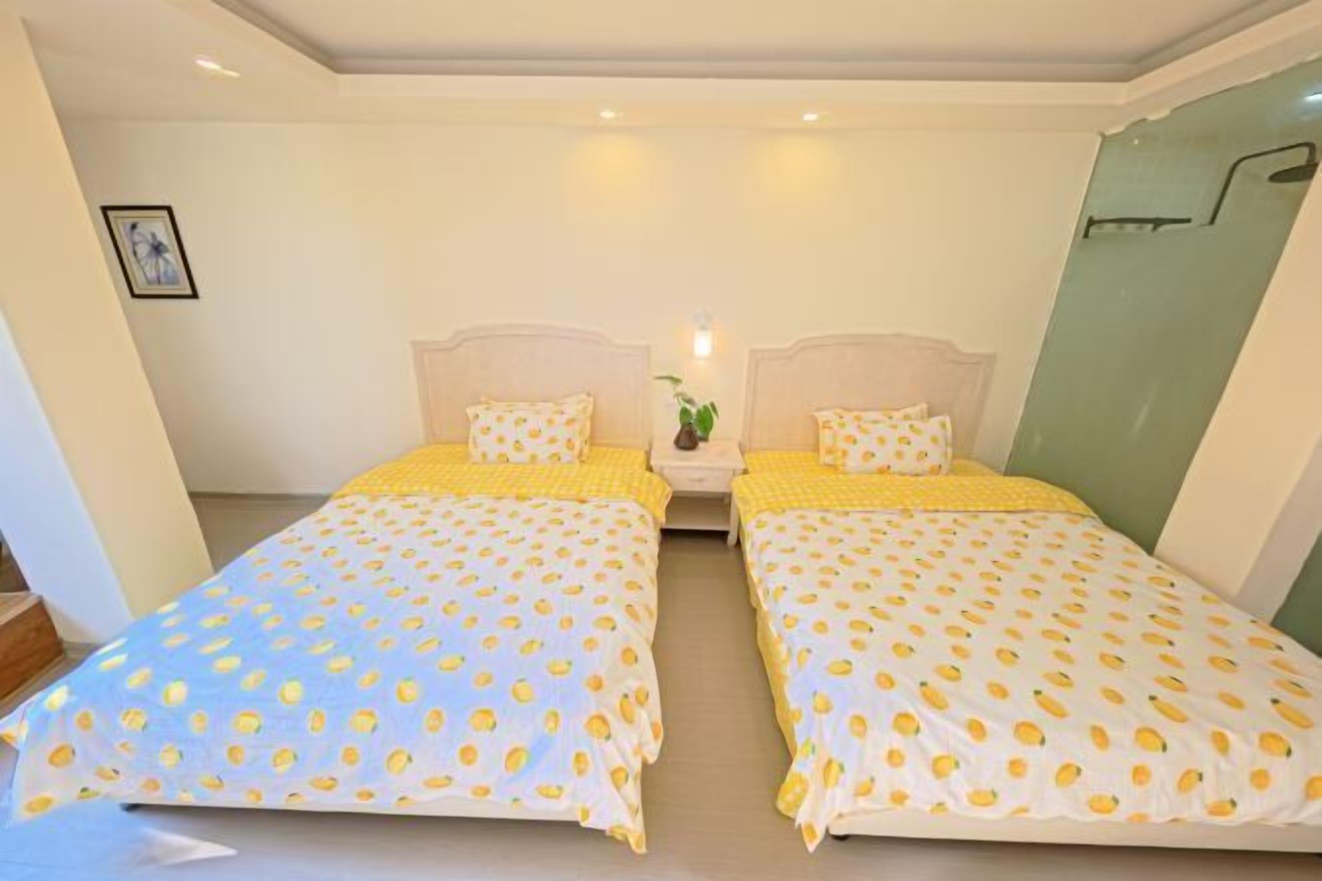A hotel room with two beds, each with a yellow and white polka dot bedspread, a nightstand with a lamp, and a framed picture on the wall.