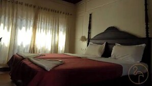 Une chambre d’hôtel avec un grand lit, une table de chevet et une fenêtre avec des rideaux.