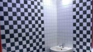 Une salle de bain avec des murs et un sol carrelés à motifs à carreaux, un lavabo et des toilettes.