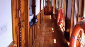 Un couloir doté d’un plancher en bois et de portes, avec des gilets de sauvetage disposés sur le côté droit.