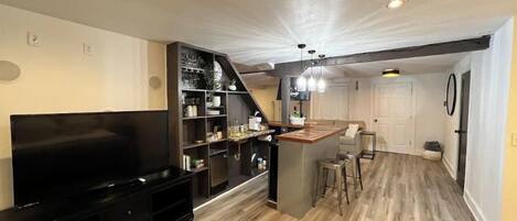 A modern kitchen with a central island, built-in shelves, and a dining area with a sofa and bar stools.