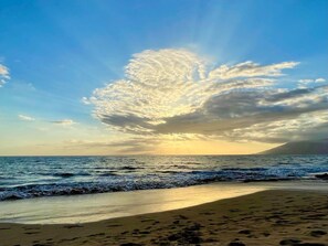 Une plage avec un ciel dégagé et une vaste formation nuageuse.