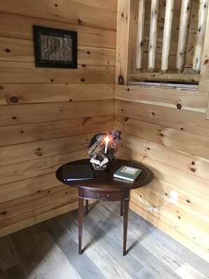 L’intérieur d’un chalet en bois, avec une petite table sur laquelle se trouvent une bougie, un livre et un objet décoratif.